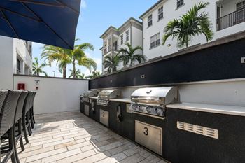 Three barbecue grills on a patio in front of a building